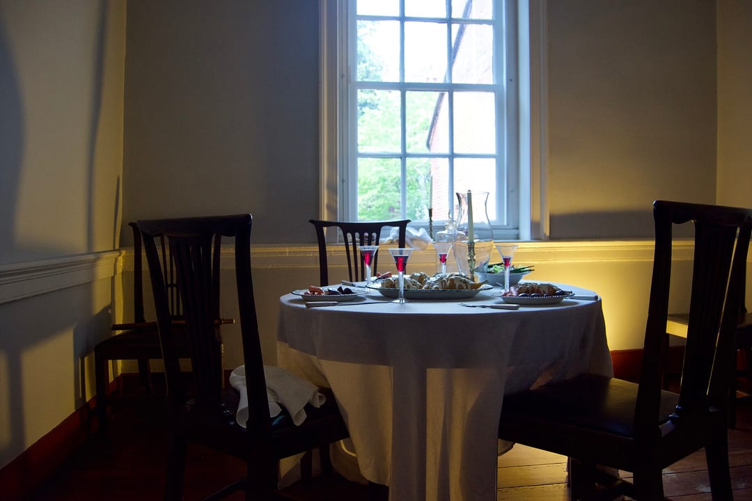 A set dining room inside Gadsby's Tavern Museum, with a laid table and period chairs.