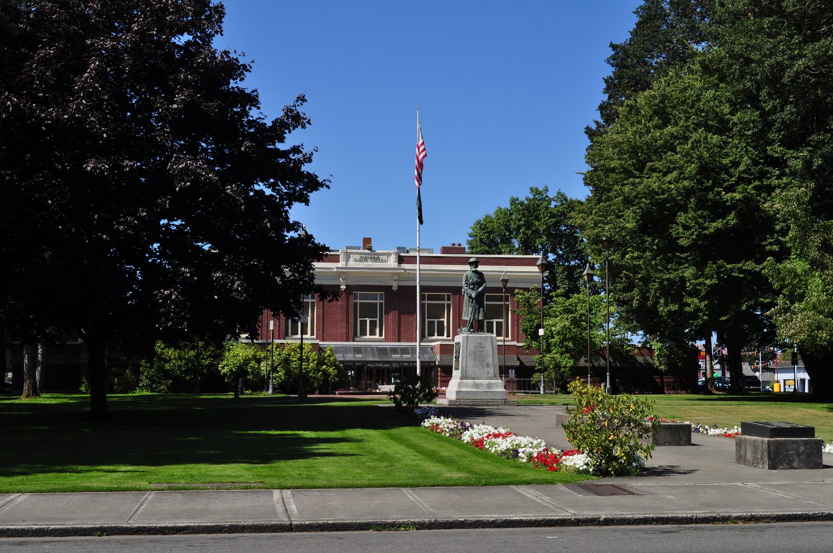 The Sentinel bronze statue in George Washington Park, Centralia, Washington, with Carnegie Library visible in background