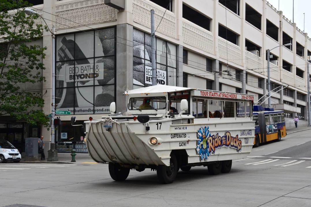 A "Ride the Ducks" amphibious tour vehicle in downtown Seattle, eastbound on Virginia Street, crossing 4th Avenue. This is duck boat No. 17.  In the righthand background, a trolleybus is laying over at its terminus.