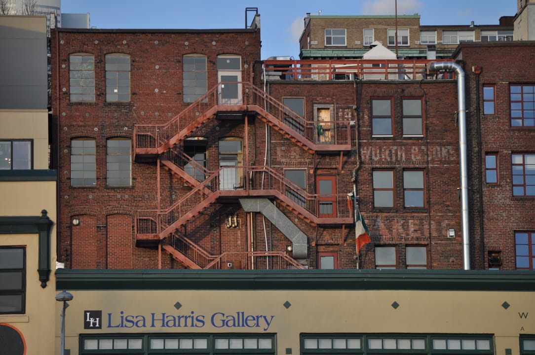 The rear (Post Alley side) of the Butterworth Building, seen from Victor Steinbrueck Park -- brick facade and fire escape above the ground-floor storefronts.