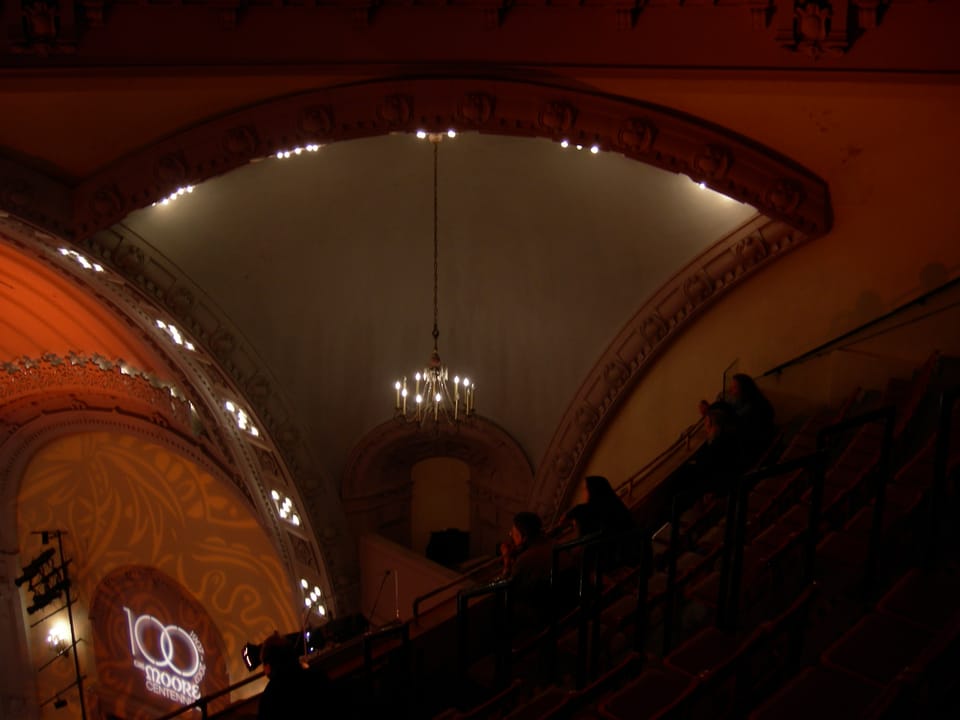The vaulted ceiling and crystal chandelier above the second balcony of the Moore Theatre, lit for the venue's 100th-anniversary open house, with a '100: The Moore Live' centennial projection on the side wall, Seattle, Washington, December 2007.