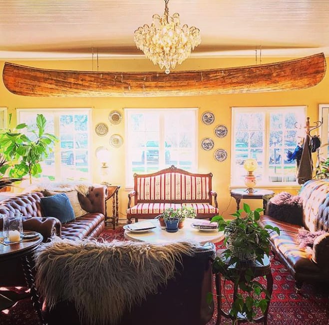 A guest sitting room at the Tokeland Hotel, with a wooden canoe hung above period furniture and antique plates on the walls.