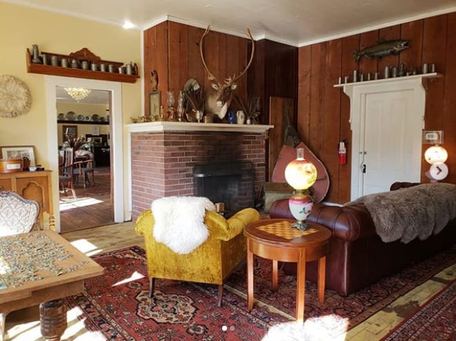 A wood-paneled parlor at the Tokeland Hotel with a brick fireplace, mounted taxidermy and leather seating.