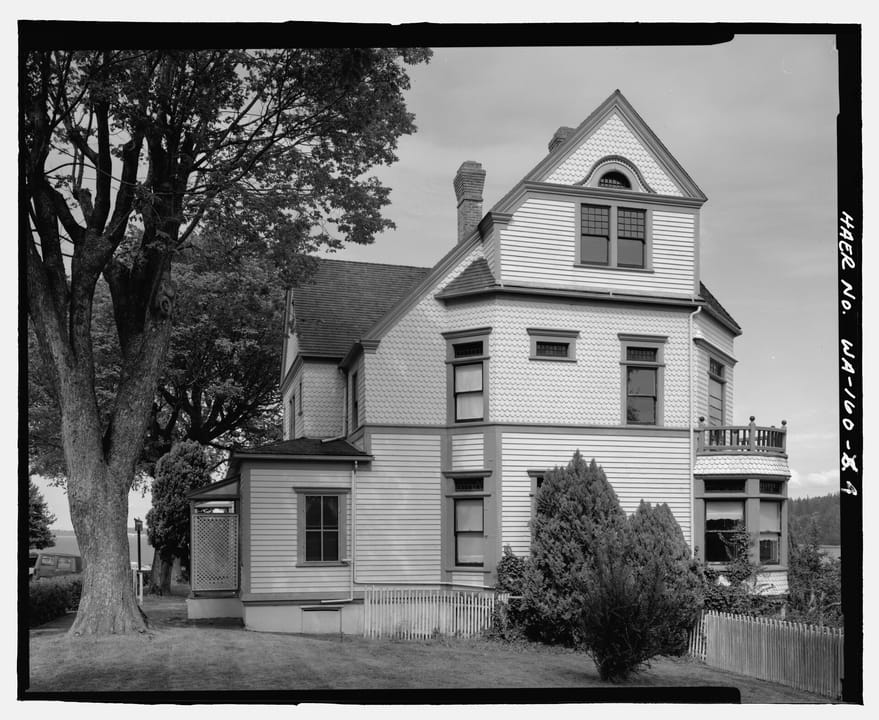 The Walker-Ames House's north elevation under a large shade tree, Rainier Avenue, Port Gamble, Washington (HAER WA-160-4).