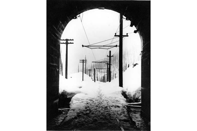 Looking out through the Cascade Tunnel toward the snow-covered tracks at Wellington, 1910 -- the reverse angle of the tunnel entrance shown in the hero photo.