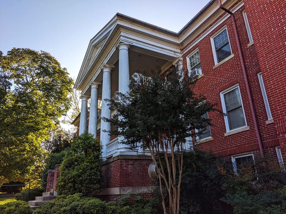 The two-storey white-columned portico and red-brick corner of Miller Hall at Shepherd University, Shepherdstown, West Virginia, seen from the side in autumn light, October 2019.