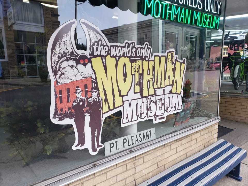 The Mothman Museum storefront on Main Street, Point Pleasant, West Virginia, with its green-and-white awning reading 'The World's Only Mothman Museum'.
