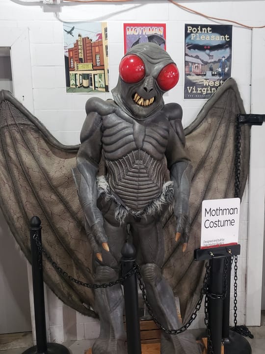 A Mothman costume prop on display inside the museum, labeled 'Mothman Costume'.