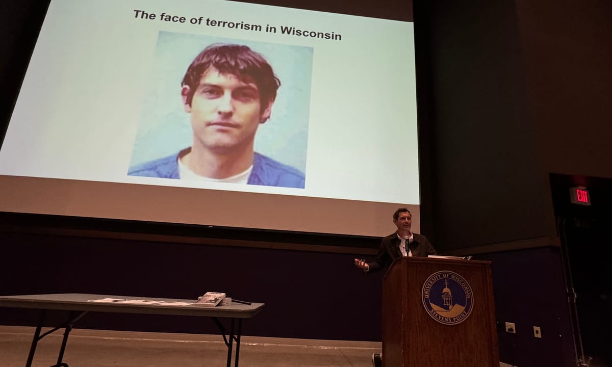 Peter Daniel Young, a convicted former terrorist, is pictured giving a speech at the University of Wisconsin-Stevens Point about "Activism in your everyday life". Young was giving the speech as a keynote speaker for Earth Week 2024. Young is pictured behind a podium with the seal of the university. 