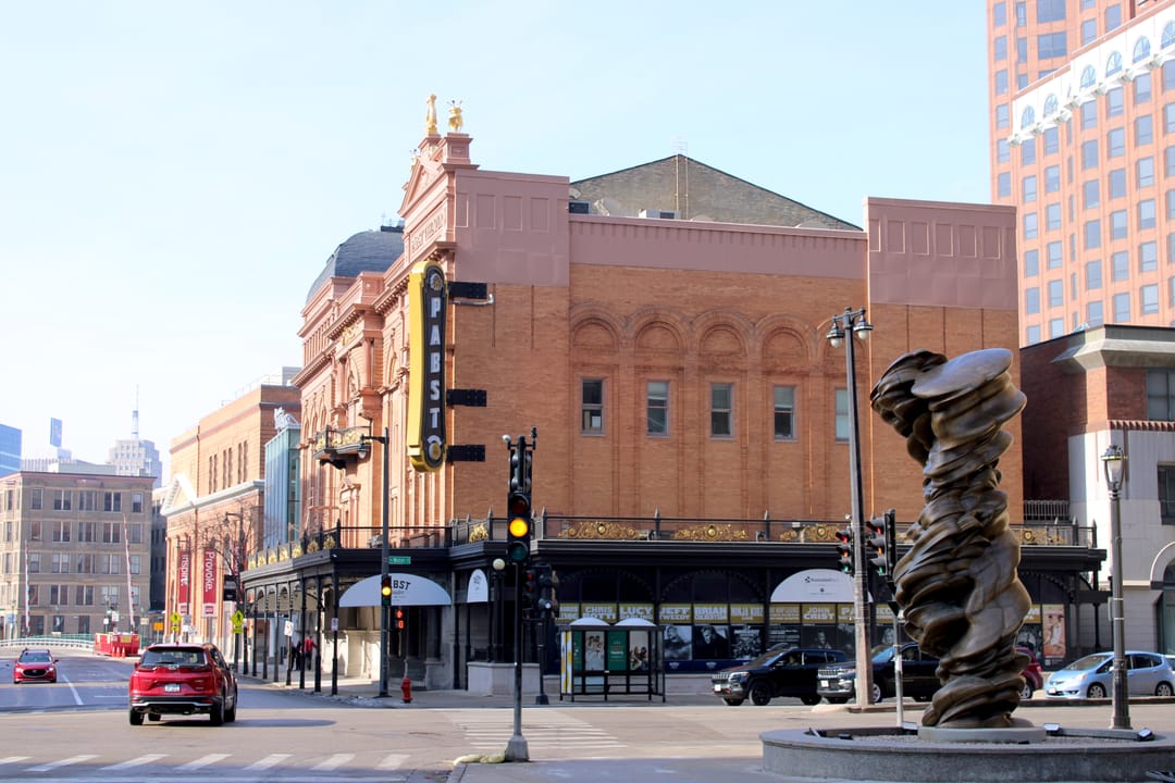 The Pabst Theater seen from the opposite street corner, with a public sculpture in the foreground, on a clear winter day