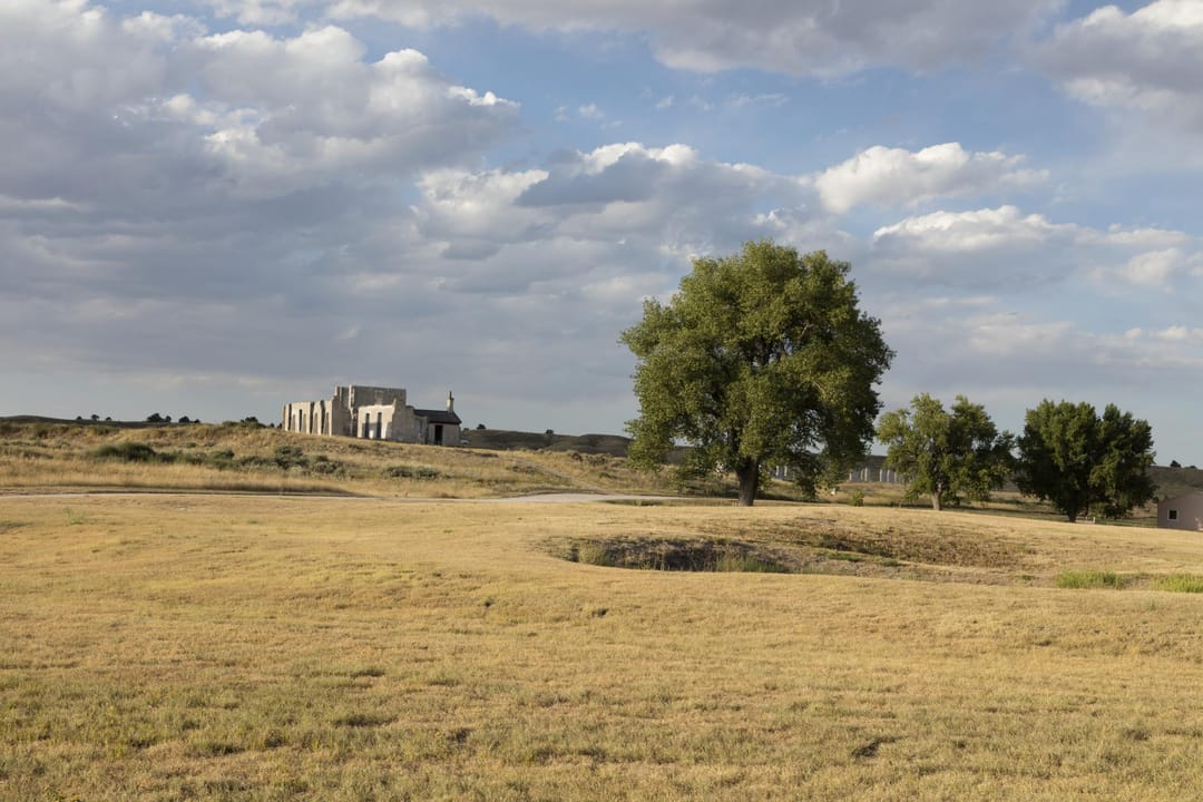 The open grounds at Fort Laramie, with the low stone foundation ruins of the post hospital in the middle distance -- the Northern Plains landscape setting of the fort.