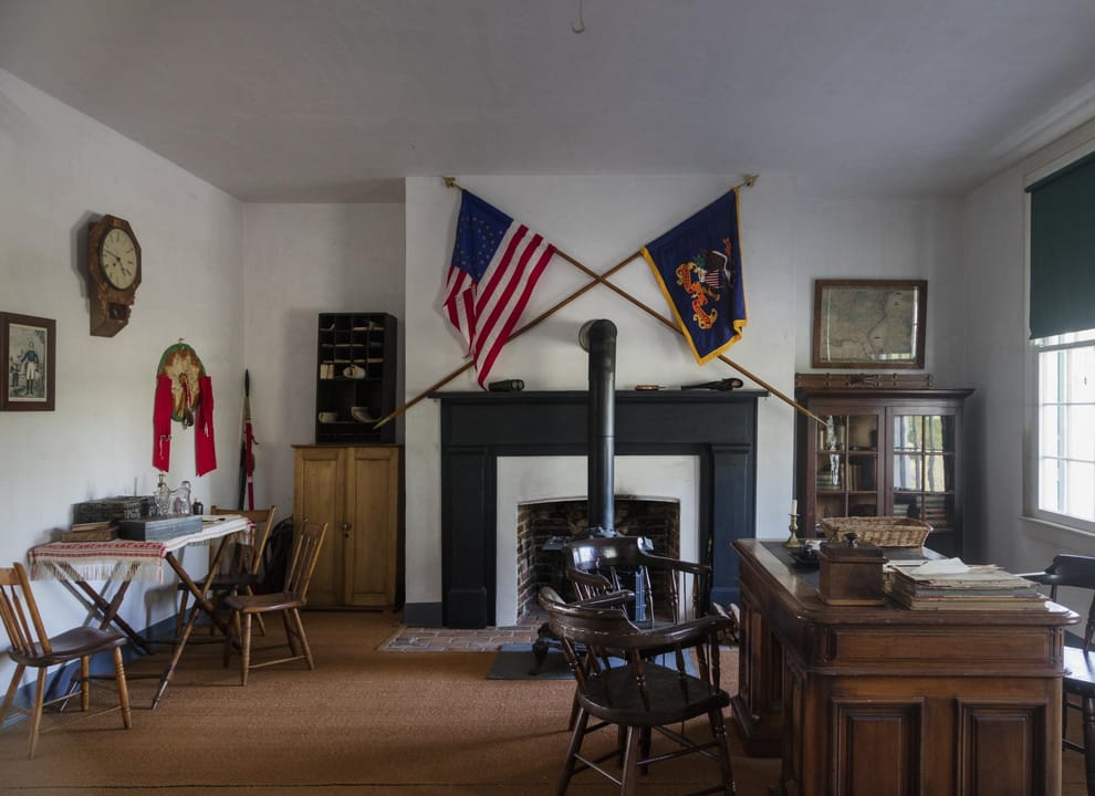 A restored officer's room inside Old Bedlam, the 1849 bachelor officers' quarters at Fort Laramie, with period furnishings, crossed flags and a fireplace.