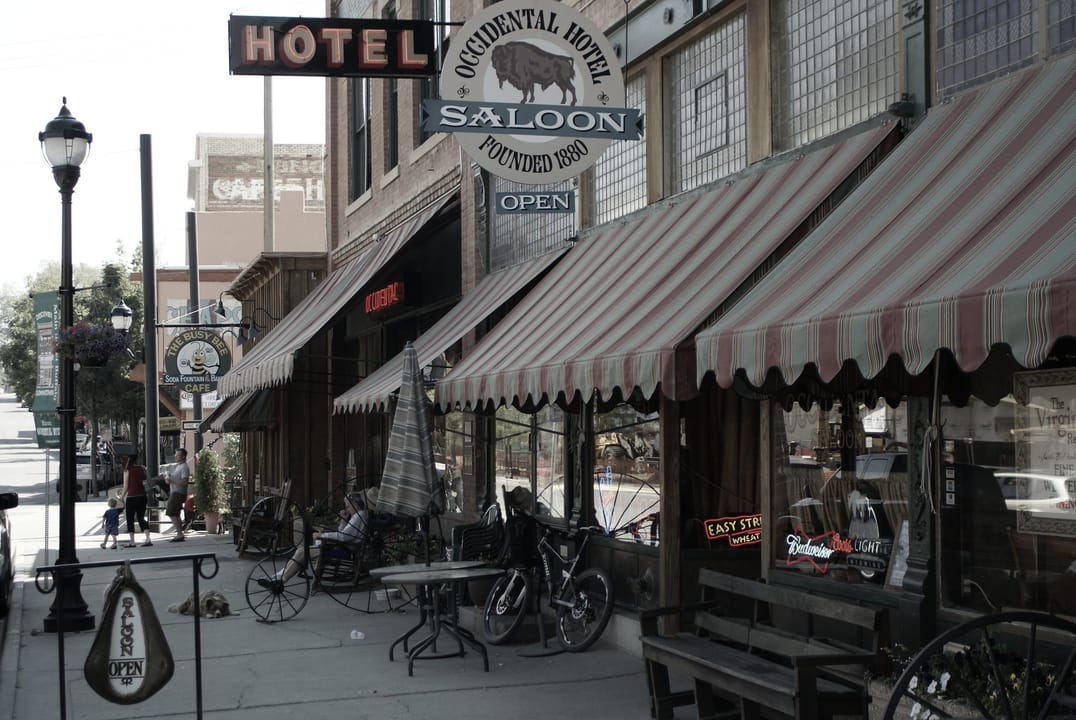 Sidewalk view of the Occidental Hotel & Saloon's striped awnings and hanging sign reading 'Occidental Hotel Saloon Founded 1880,' Buffalo, Wyoming, 2012.