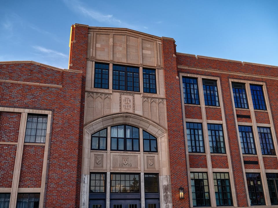 Entrance bay of the Laramie Plains Civic Center, the former East Side School, in red brick with a stone-framed arch and a datestone reading 1878 and 1926, with 1939 on the panel below, Laramie, Wyoming.