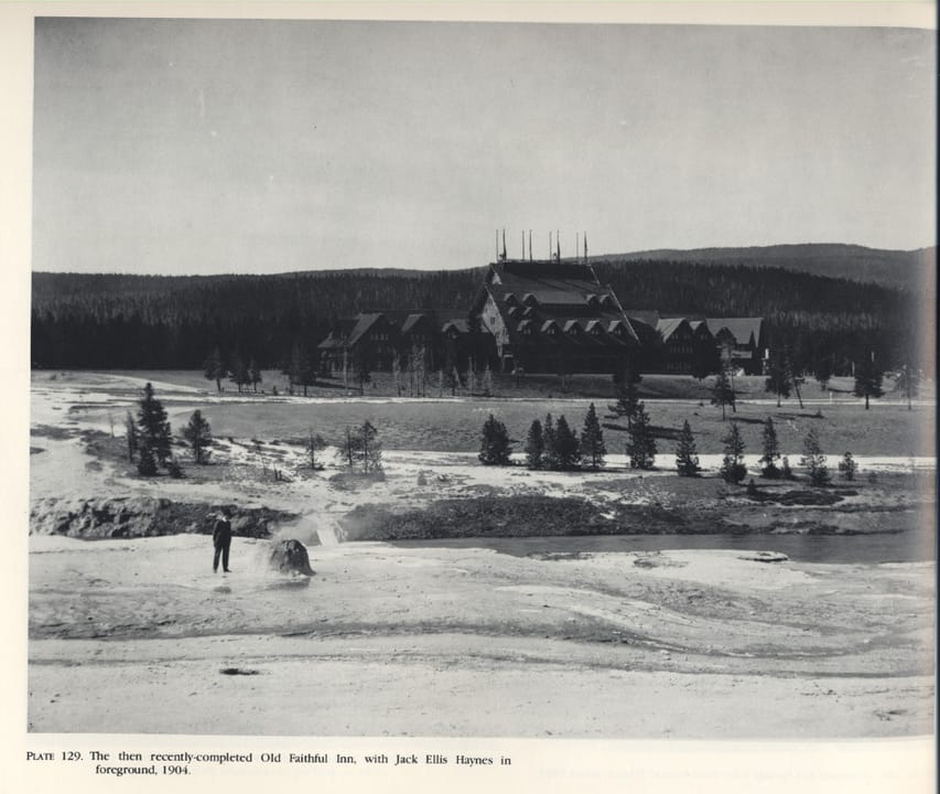 The newly completed Old Faithful Inn seen across the geyser basin, with Jack Ellis Haynes in the foreground, 1904 -- the year it opened.
